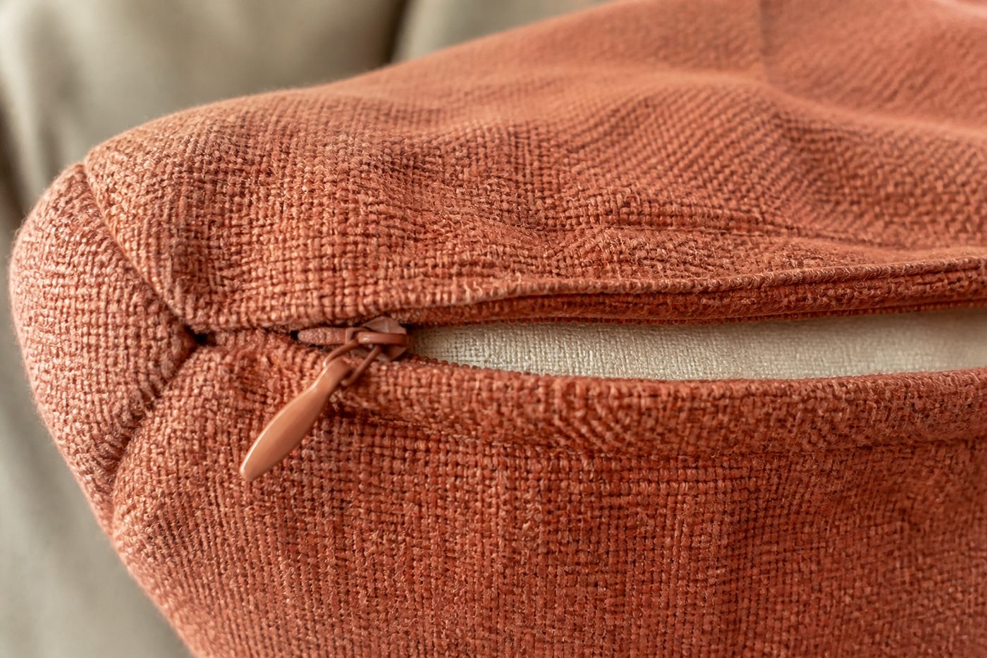 Close-up van geweven linnen in terracotta met een rits in de zijnaad